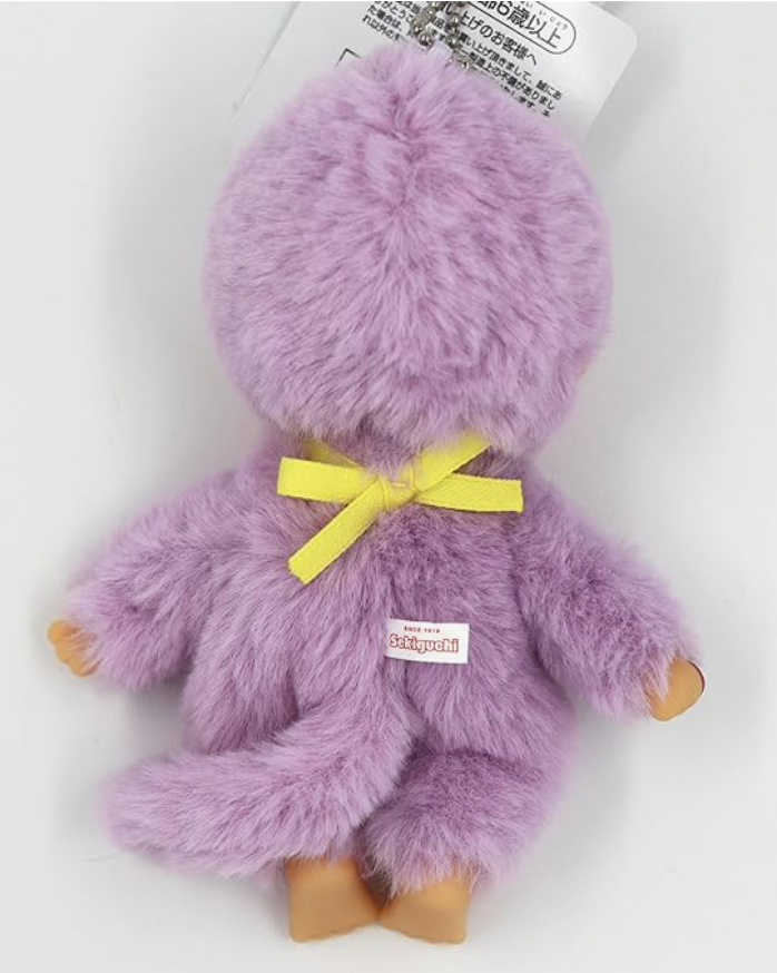Purple fluffy toy with a yellow bow on a white background
